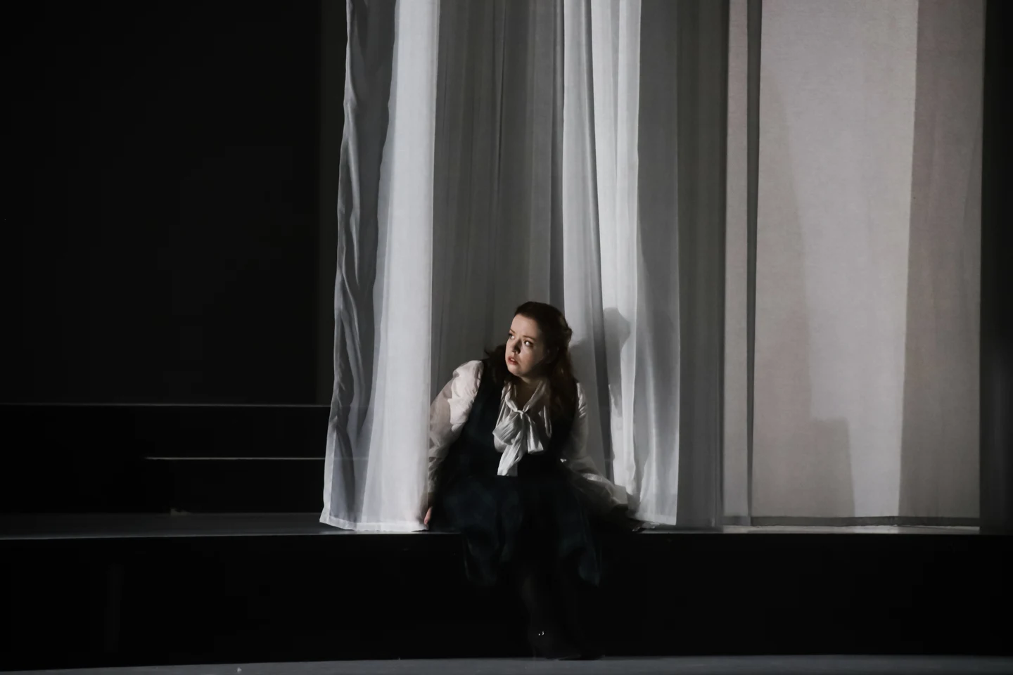 Donata Meyer-Kranixfeld in a dramatic stage scene with tall translucent curtains